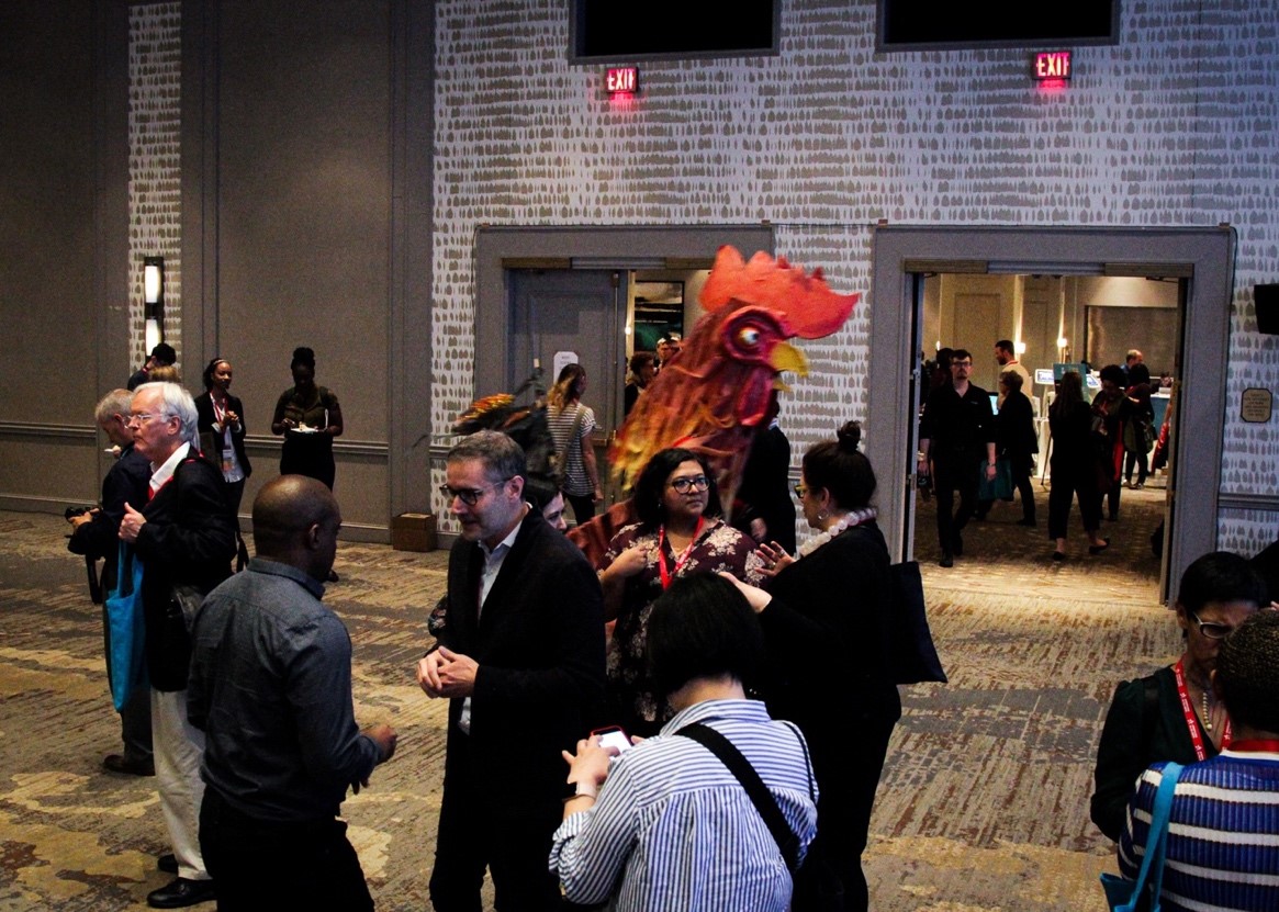 A puppeteer in a handmade rooster suit carouses with Convention attendees. The costume was part of an earlier puppetry performance. 