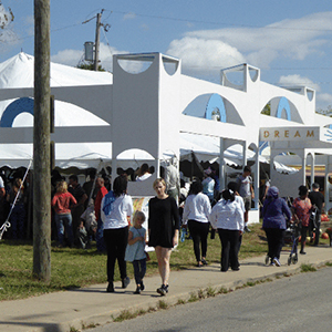 PreEnactIndy attendees walk along the street and watch performances in the pop-up Dream Theater.