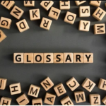 A photo of small wood letter tiles spelling out the word "glossary."